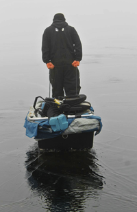 image of ice fisherman walking on ice with standing water