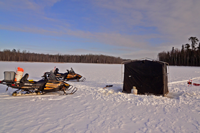 image of snowmobiles and portable shelter on ice