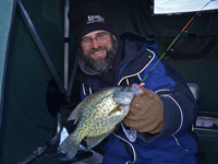 image of Jeff Samsel holding Crappie in ice fishing shelter
