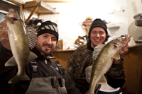 image of Nik Dimich and Justin Harms holding Walleyes inside of fishing shelter